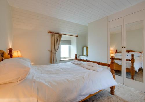 a bedroom with a large white bed and a mirror at Kelynack in Porthleven