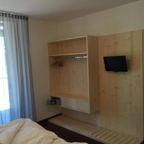 a bedroom with a wooden cabinet with a tv on it at Komodo short stay apartments in Trento