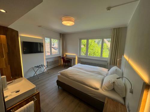 a bedroom with a bed and a sink and windows at Hotel Drei Könige in Chur