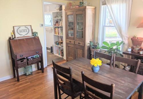 a dining room with a wooden table and a piano at Victory Garden Cottage 12 min to downtown with fire pit and in Asheville