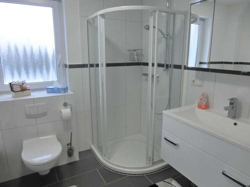 La salle de bains blanche est pourvue d'une douche et de toilettes. dans l'établissement Glowe Doppelferienhaus Sonnenstrand, à Glowe