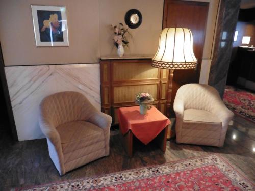a living room with two chairs and a table and a lamp at Hotels Landhaus Dieterichs in Wolfsburg