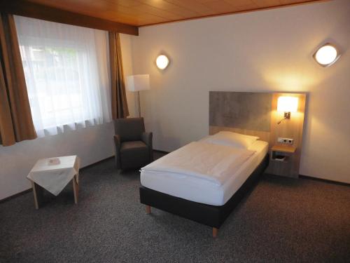 Habitación de hotel con cama y silla en Hotels Landhaus Dieterichs en Wolfsburg