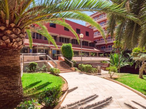 uma palmeira em frente a um edifício em Seramar Hotel Luna Park Adults Only em El Arenal