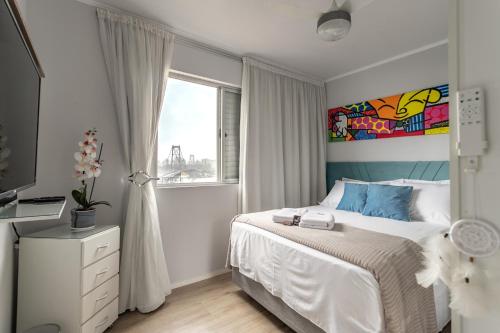 フロリアノポリスにあるMagnífico "QUARTO" Privativo em Apto, com Vista Espetacularの白いベッドルーム(ベッド1台、窓付)