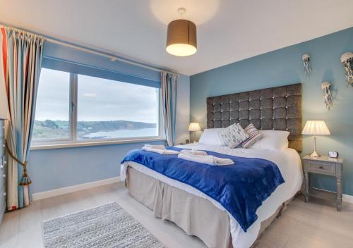 een blauwe slaapkamer met een groot bed en een groot raam bij Dawn End in Looe
