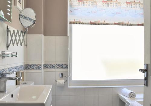 een badkamer met een wastafel en een raam bij Dawn End in Looe