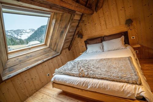 a bed in a wooden room with a window at La grange au ruisseau in Bellecombe-en-Beauges