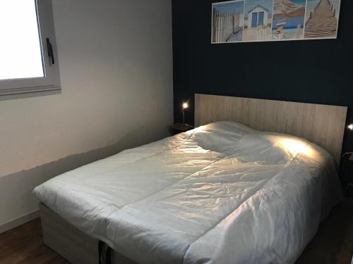 une chambre avec un lit avec des draps blancs et une fenêtre dans l'établissement Appartement près de la plage avec balcon et parking privé - FR-1-336-69, à Longeville-sur-Mer