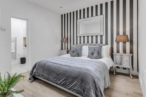 a bedroom with a bed with a striped wall at We Stay Baxter Gate 3 Bedroom Apartment in Loughborough