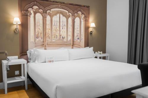 1 dormitorio con 1 cama blanca grande y cabecero ornamentado en Mesón Castilla Atiram Hotels, en Barcelona