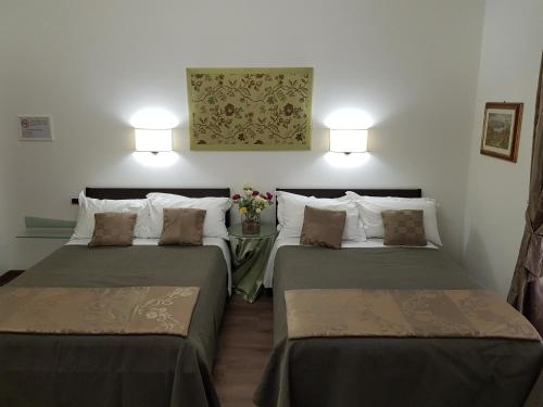 two beds in a room with a table with flowers at L'Insolita Reggia in Caserta