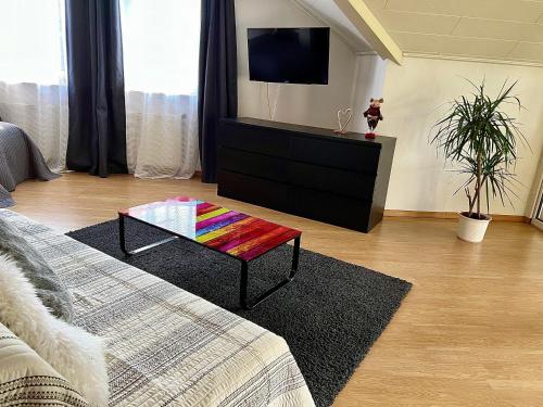 uma sala de estar com televisão e uma mesa de centro colorida em Pension Marco em Trendelburg
