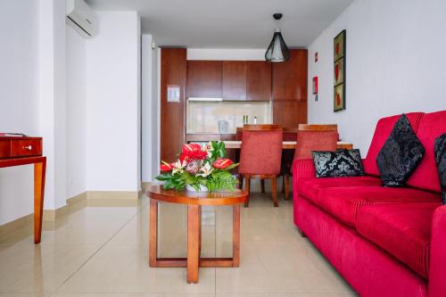 a living room with a red couch and a table with flowers at Muthu Clube Praia da Oura in Albufeira