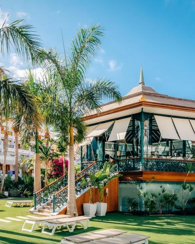 a building with palm trees in front of it at Parque Santiago III Official in Playa de las Americas