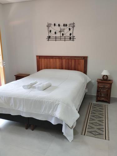a bedroom with a large white bed with white sheets at Pouso Casa da Vovó in Tiradentes
