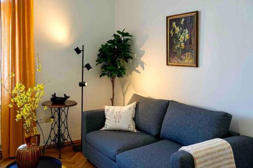 a living room with a blue couch and a plant at Stilvolles Apartment im Zentrum in Graz
