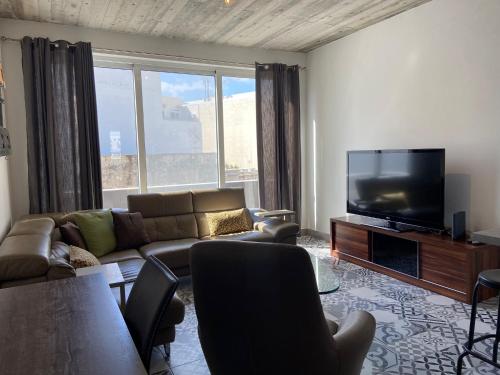 a living room with a couch and a flat screen tv at Sliema Distant Seaview Penthouse in Sliema