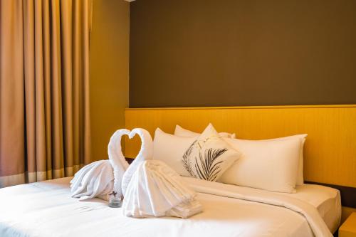 two swans dressed in white are sitting on a bed at Greystone 99 Suites in Melaka