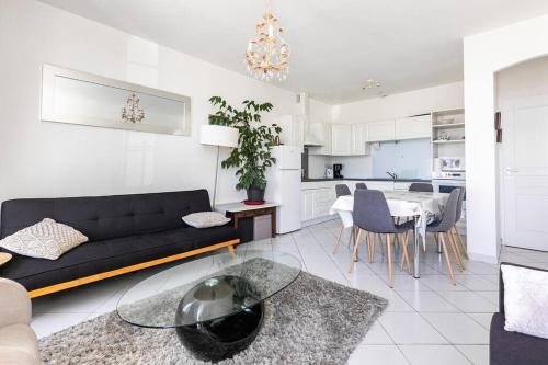 un salon avec un canapé noir et une table dans l'établissement Charmante maison à 10 minutes à pied de la plage, à Saint-Georges-de-Didonne