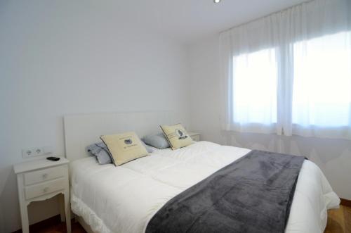 um quarto branco com uma cama e uma janela em Apartamentos Front Mar em L'Escala