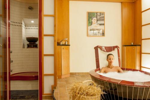 a man sitting in a bath tub in a bathroom at Hotel Nevada in Samnaun