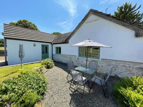 a patio with a table and chairs and an umbrella at Oaktree Cottage, West Atheston Farm in Narberth
