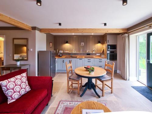 a living room with a red couch and a table at Luxury Lodge @ Ewen Barn - private 5* retreat in Cirencester