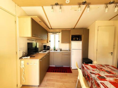 una pequeña cocina con nevera blanca y mesa en Bungalow L'Estagnol - 3 chambres en Sigean