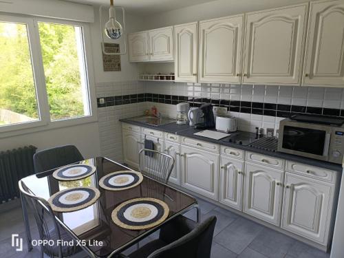 una cocina con armarios blancos y una mesa con platos. en coté jardin, en Questembert