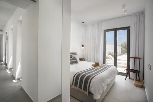 a white bedroom with a bed and a balcony at STONE VILLA NAXOS in Naxos Chora
