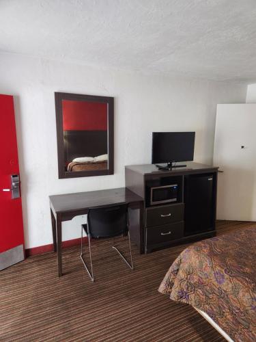 Habitación de hotel con escritorio, TV y cama en regency inn, en Gainesville