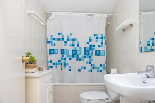 a bathroom with a toilet and a sink and a shower curtain at RVHotels Apartamentos Els Salats in L'Estartit