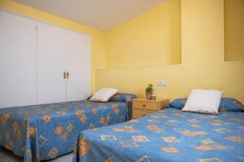 2 camas en una habitación con paredes amarillas en RVHotels Apartamentos Els Salats, en L'Estartit