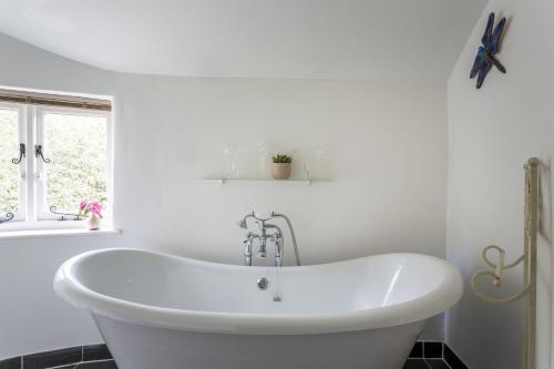a white bath tub in a bathroom with a window at Mythra Cottage in Stokenham