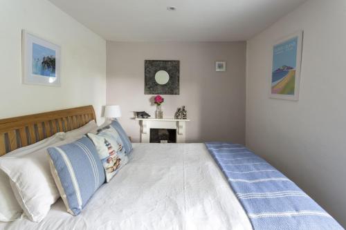 a bedroom with a large white bed with blue pillows at Mythra Cottage in Stokenham