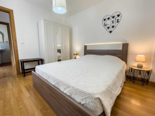 a bedroom with a large white bed and two lamps at Évora City Break Apartment with Patio in the Historic Centre in Évora