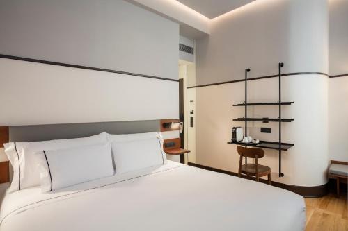 a bedroom with a large white bed and a shelf at Praktik Èssens in Barcelona