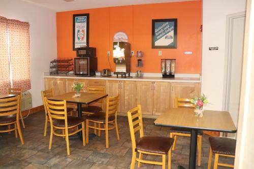 a restaurant with two tables and a kitchen with orange walls at Howard Johnson by Wyndham Tifton GA I-75 in Tifton