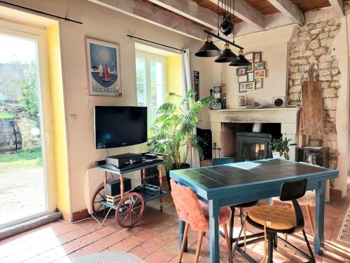 a dining room with a blue table and a tv at Le calme de la campagne proximité Center Parcs in Saint-Léger-de-Montbrillais
