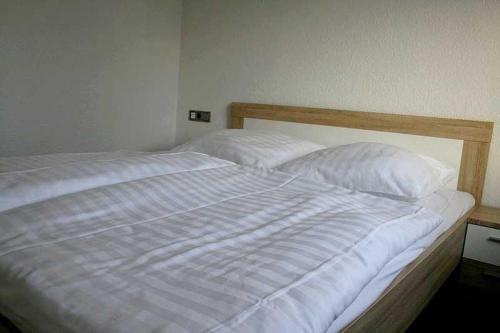 uma cama branca com lençóis e almofadas brancos em Ferienwohnung Sassnitz em Sassnitz