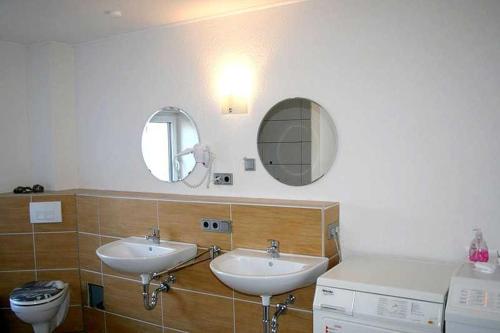 a bathroom with two sinks and a toilet and mirrors at Ferienwohnung Sassnitz in Sassnitz