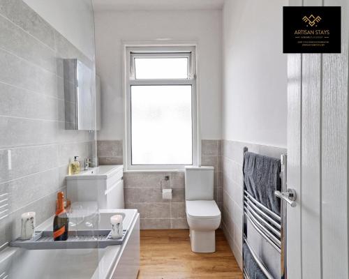 a bathroom with a sink and a toilet and a window at Deluxe Apartment in Southend-On-Sea by Artisan Stays I Long Stay Offer I Relocation or Business in Southend-on-Sea