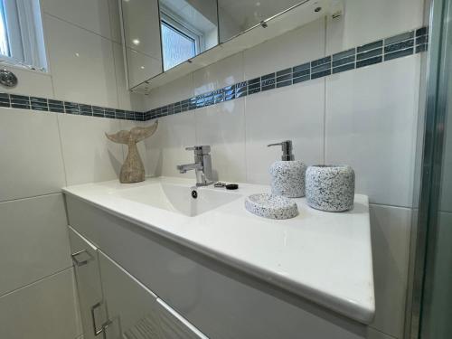 Un baño blanco con lavabo y espejo. en Quaint 2 Bed Village Retreat, en Pevensey