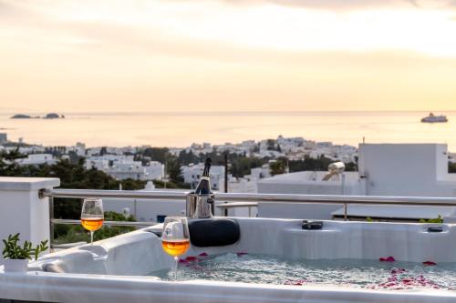 a hot tub with two glasses of wine on a balcony at Panos Villa Sunset View in Parikia