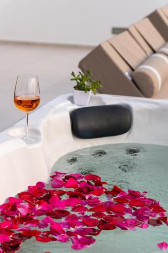a glass of wine and pink flowers in a bath tub at Panos Villa Sunset View in Parikia