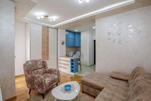 a living room with a couch and a clock on the wall at ApartmentJakovNiksic in Nikšić