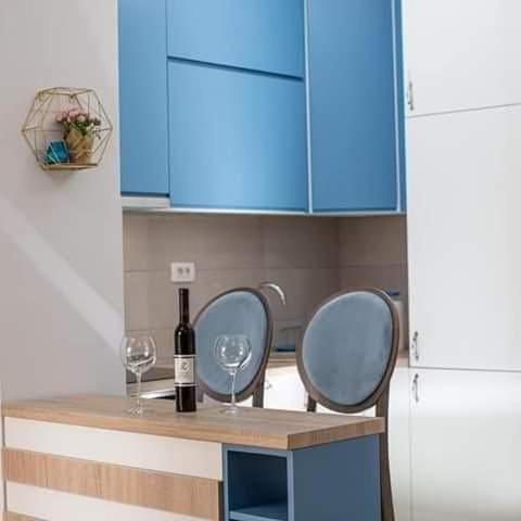 a kitchen with blue cabinets and two glasses of wine at ApartmentJakovNiksic in Nikšić