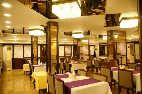 un restaurante con mesas blancas, sillas y luces en Alfin Hotel, en Ankara