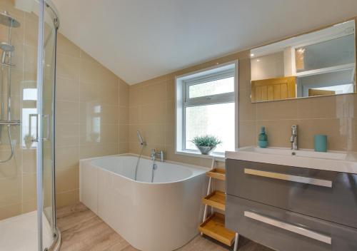 a bathroom with a tub and a sink and a shower at Lindos in Looe